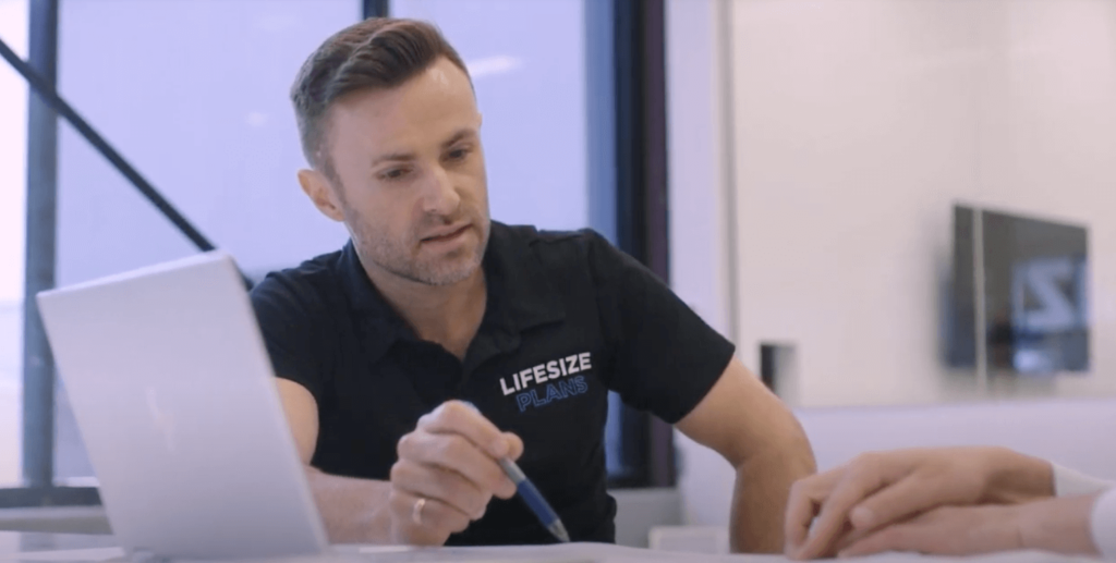 A man in a black shirt focused on his laptop, typing away with determination.